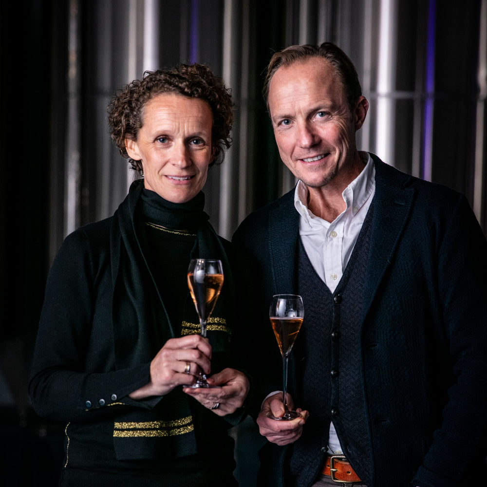 Charles and Ruth Simpson smiling and holding a glass of wine each